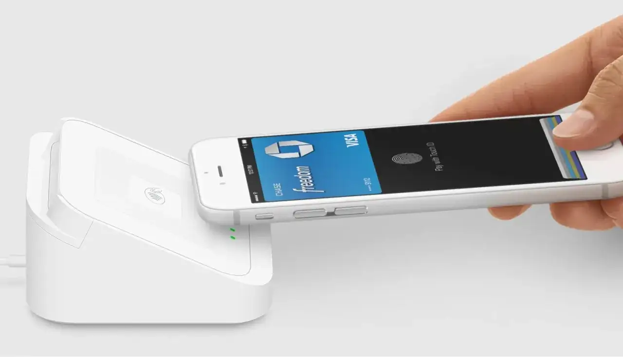 Płatność zbliżeniowa iPhone'em z wykorzystaniem technologii NFC. Karta Chase Freedom Visa zbliża się do terminala płatniczego.
