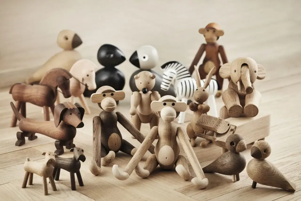 En samling av ikoniska tr&auml;figurer fr&aring;n Kay Bojesen, inklusive apor, elefanter, hundar och h&auml;star, st&aring;r p&aring; ett tr&auml;golv.
