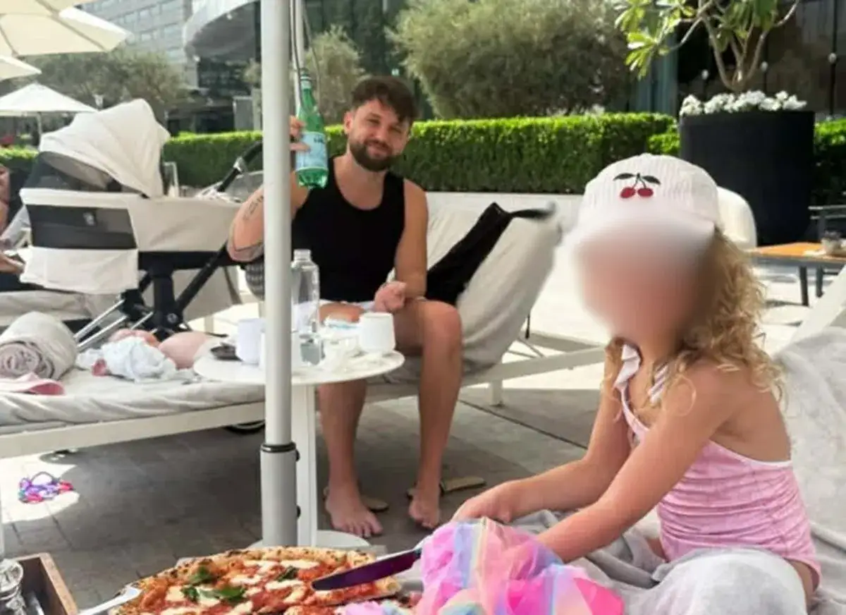 Mężczyzna z butelką wody i pizza na stole, obok wózek z dzieckiem. Czy to początek afery dubajskiej?