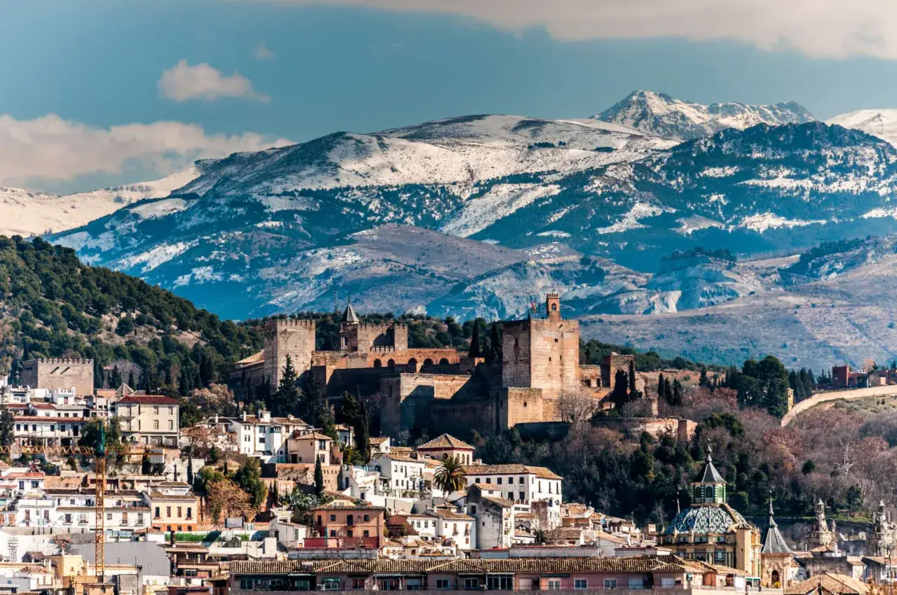 Die Alhambra thront &uuml;ber Granada, ein beeindruckender Anblick im winterlichen Spanien. Schneebedeckte Berge bilden die majest&auml;tische Kulisse.