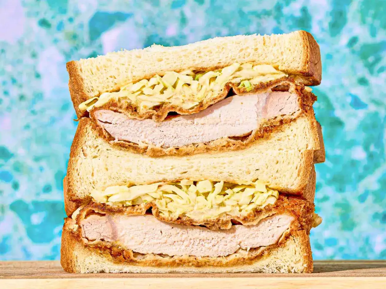 Zwei übereinander gestapelte Katsu Sando mit saftigem Schnitzel und knackigem Krautsalat zwischen weichem Toastbrot.