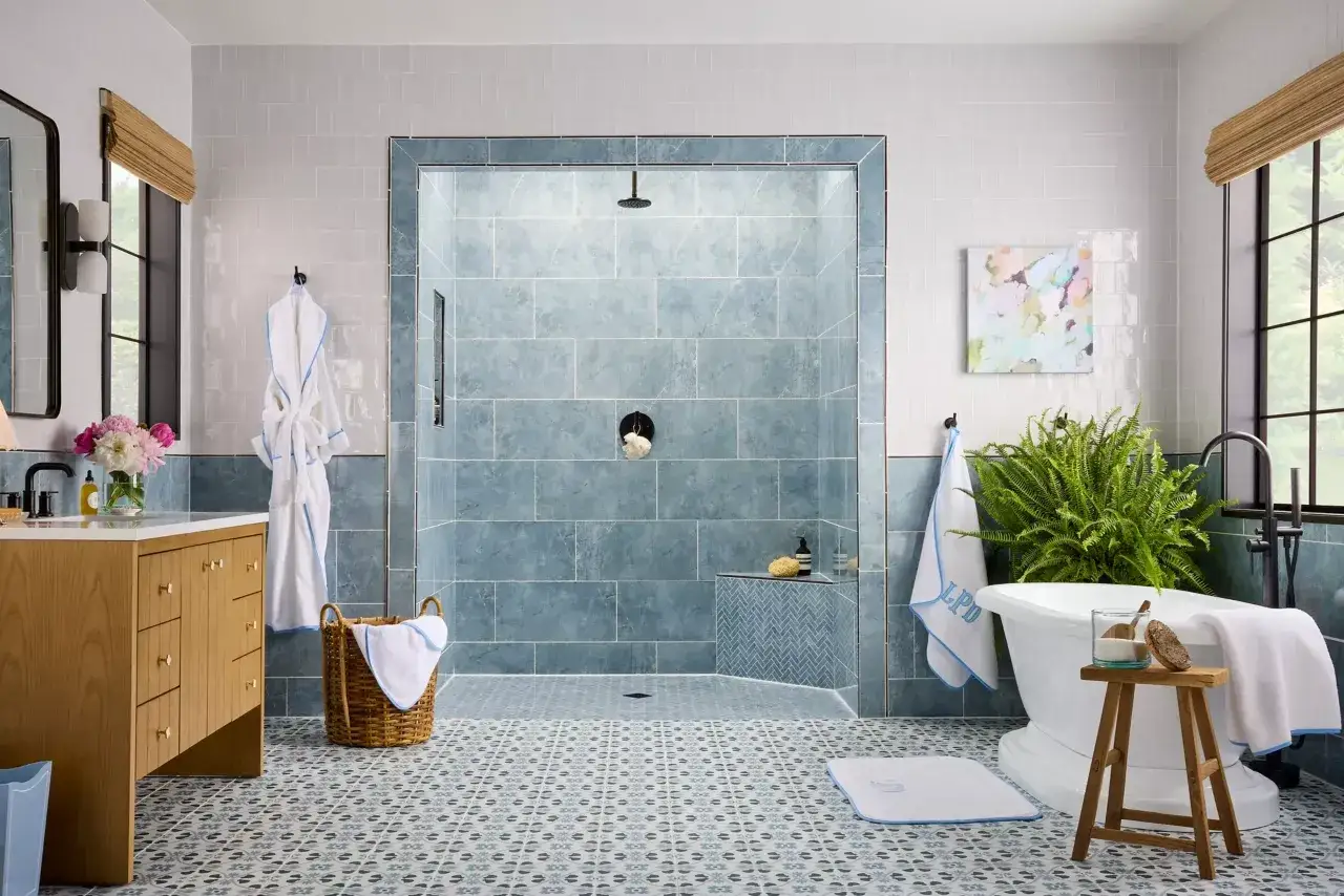 Elegant bathroom with blue tiled shower and patterned floor. The shower floor designs feature a mosaic pattern, complementing the overall serene aesthetic.