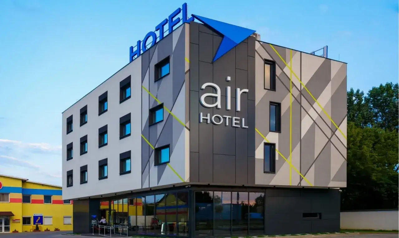 Nowoczesny hotel Air przy lotnisku WAW. Budynek z geometrycznymi wzorami i niebieskim logo.