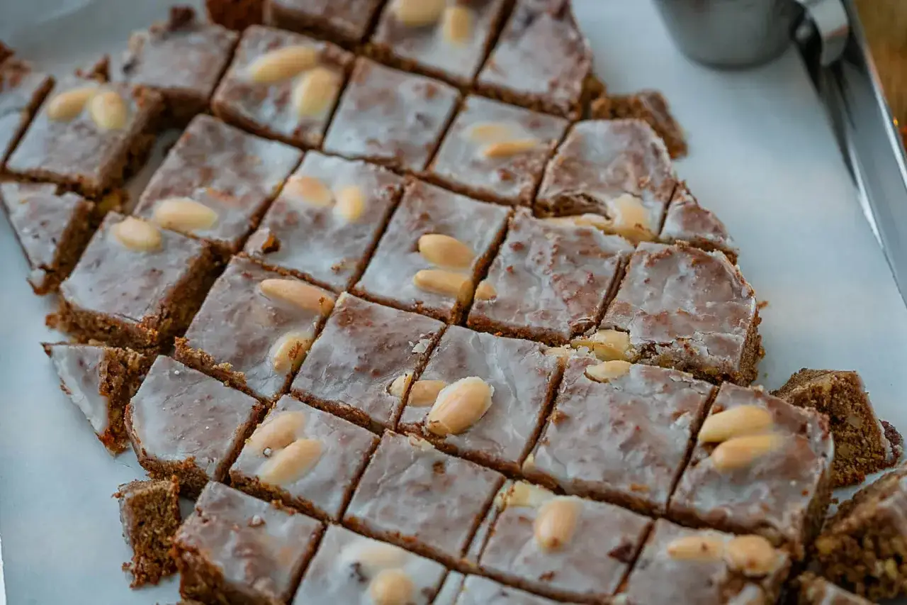 Rechteckige Elisenlebkuchen vom Blech, mit Zuckerguss und Mandeln belegt, bereit zum Genießen.