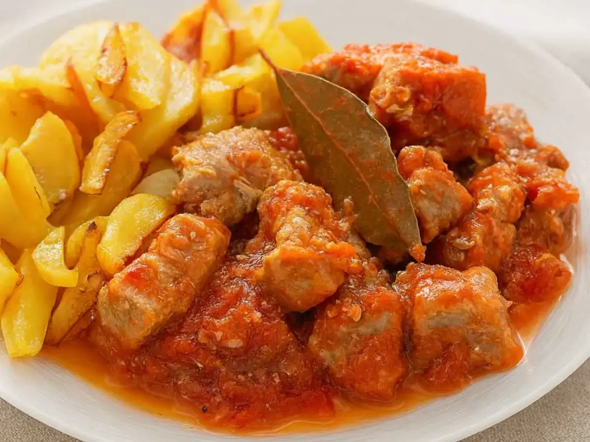 Sabroso magro con tomate, jugosos trozos de carne en salsa roja, acompa&ntilde;ados de patatas fritas doradas.