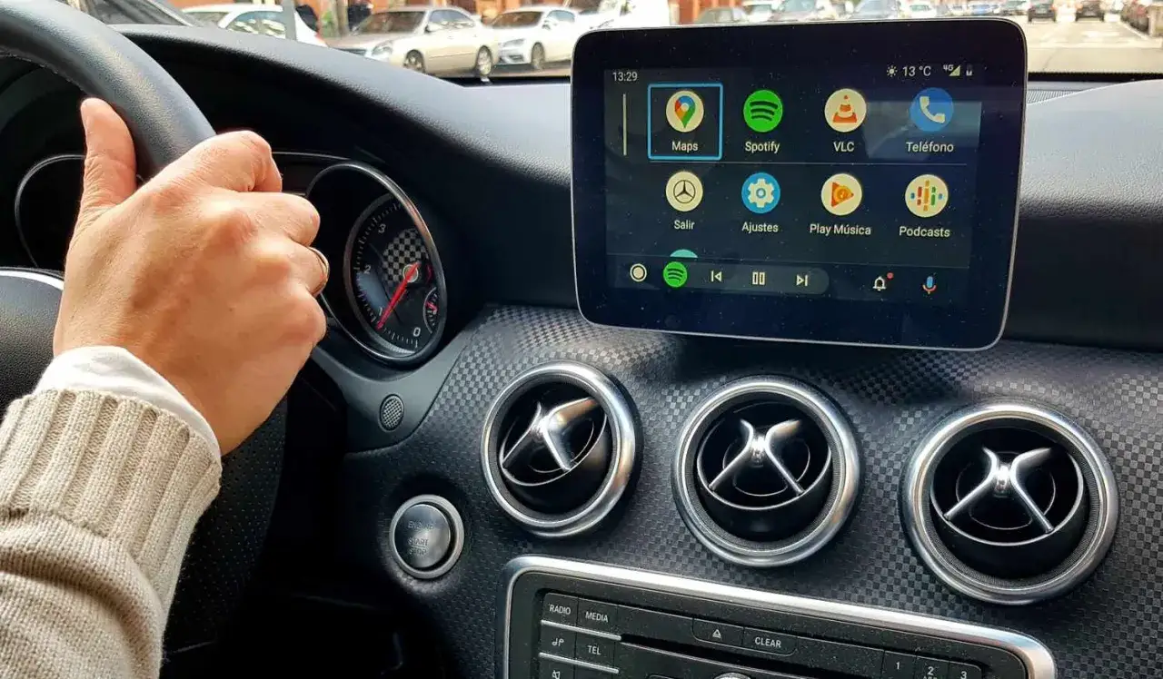 Ręka na kierownicy, ekran multimediów pokazuje ikony aplikacji, ale **apple carplay nie działa**.