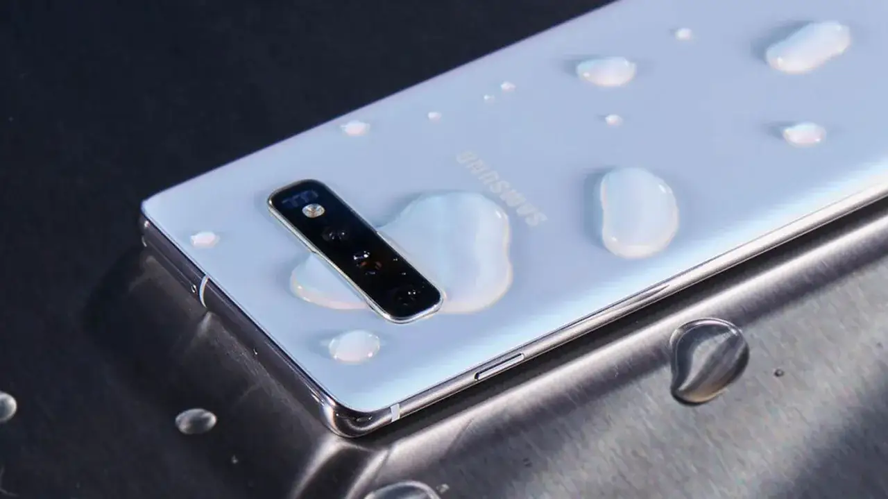 Biały, wodoodporny smartfon Samsung z kroplami wody na obudowie i aparacie.