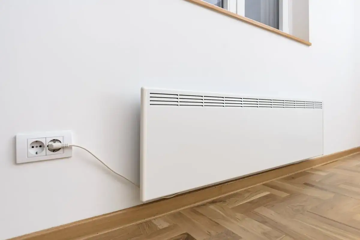 Termoconvettori bianchi montati a parete, uno collegato a una presa elettrica, pronti a riscaldare l'ambiente.
