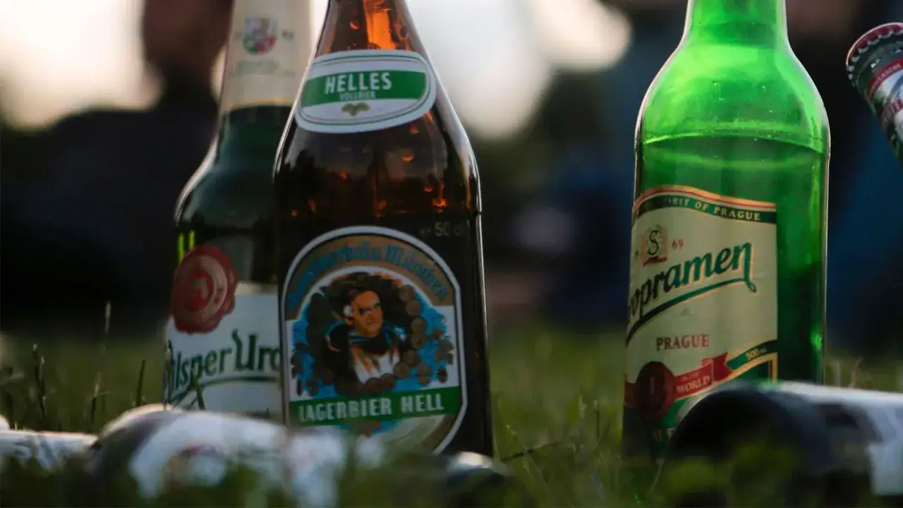 Augustiner Edelstoff Test: Mehrere Bierflaschen, darunter Augustiner Lagerbier Hell und Staropramen, stehen im Gras.