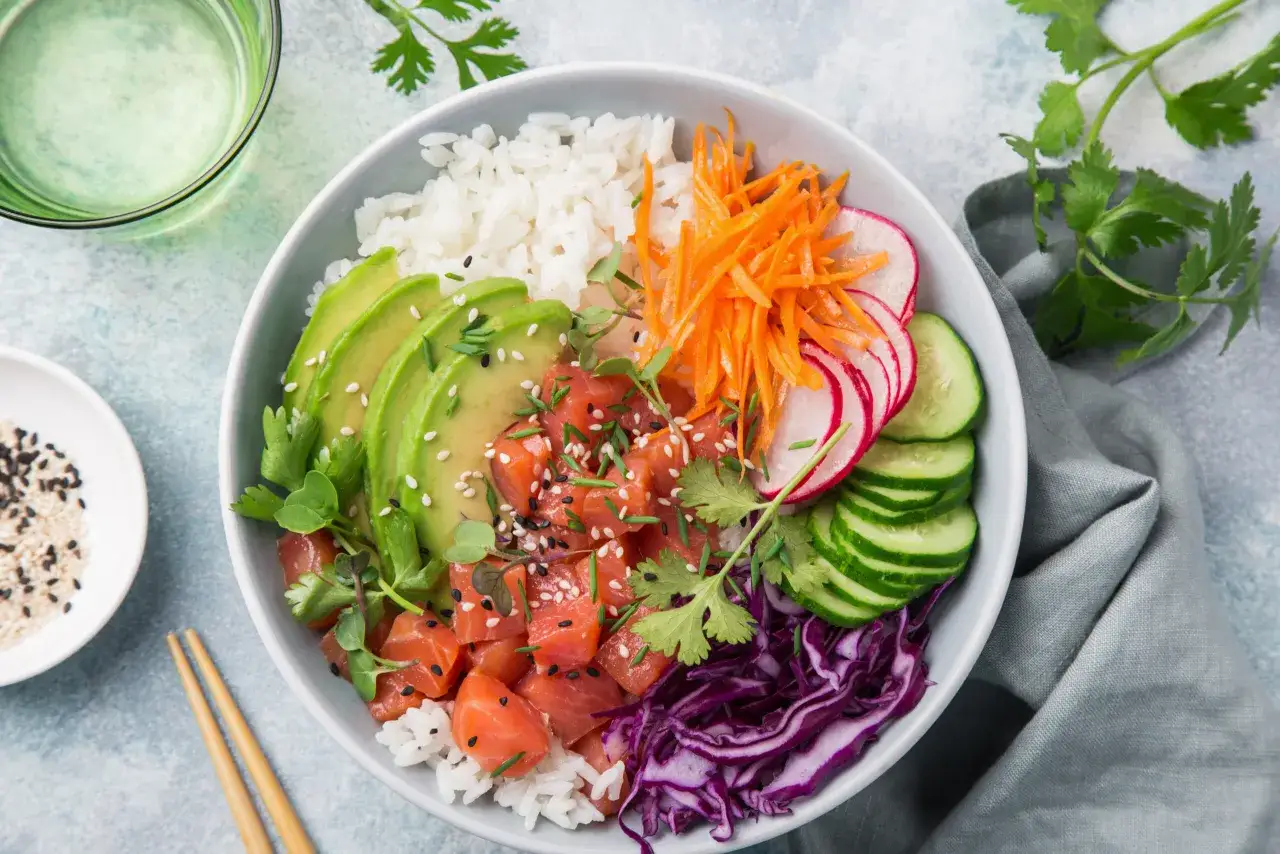Kolorowa bowl sushi z łososiem, awokado, ryżem, marchewką, rzodkiewką i og&oacute;rkiem.