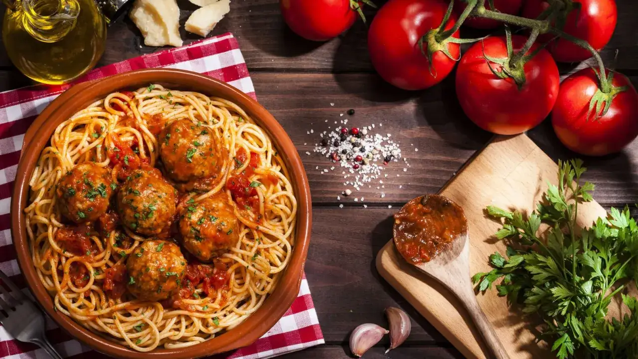 Un plat de spaghetti aux boulettes de viande, un classique des recettes p&acirc;tes italiennes traditionnelles. Tomates fra&icirc;ches, ail et persil compl&egrave;tent la sc&egrave;ne.