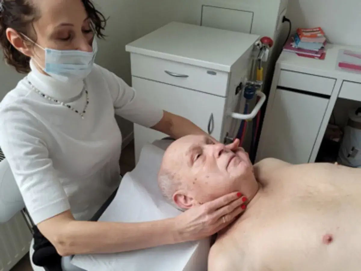 Terapeuta wykonuje masaż twarzy, aby złagodzić obrzęk limfatyczny.