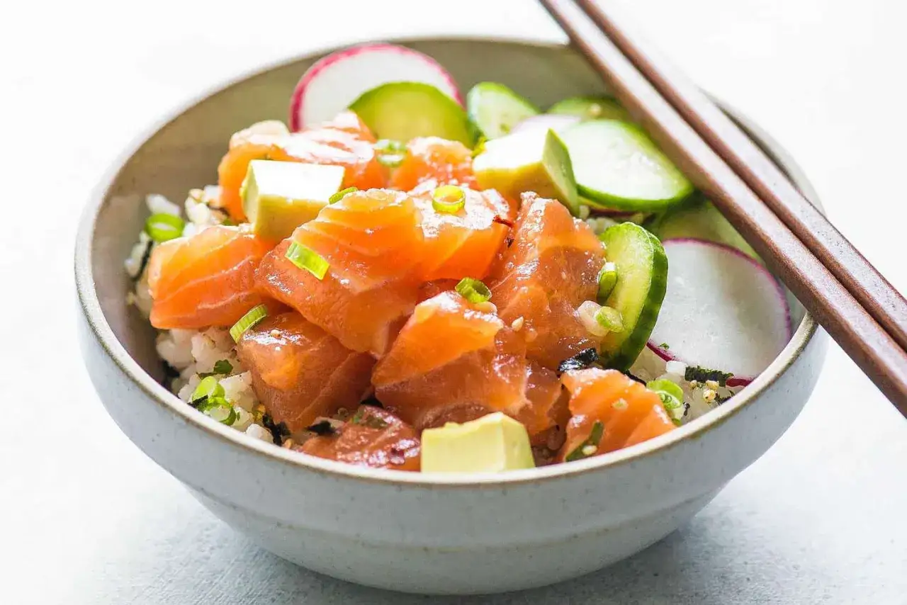 En skål med lax poke, ris, gurka, rädisa och avokado. En hälsosam och färgglad måltid.