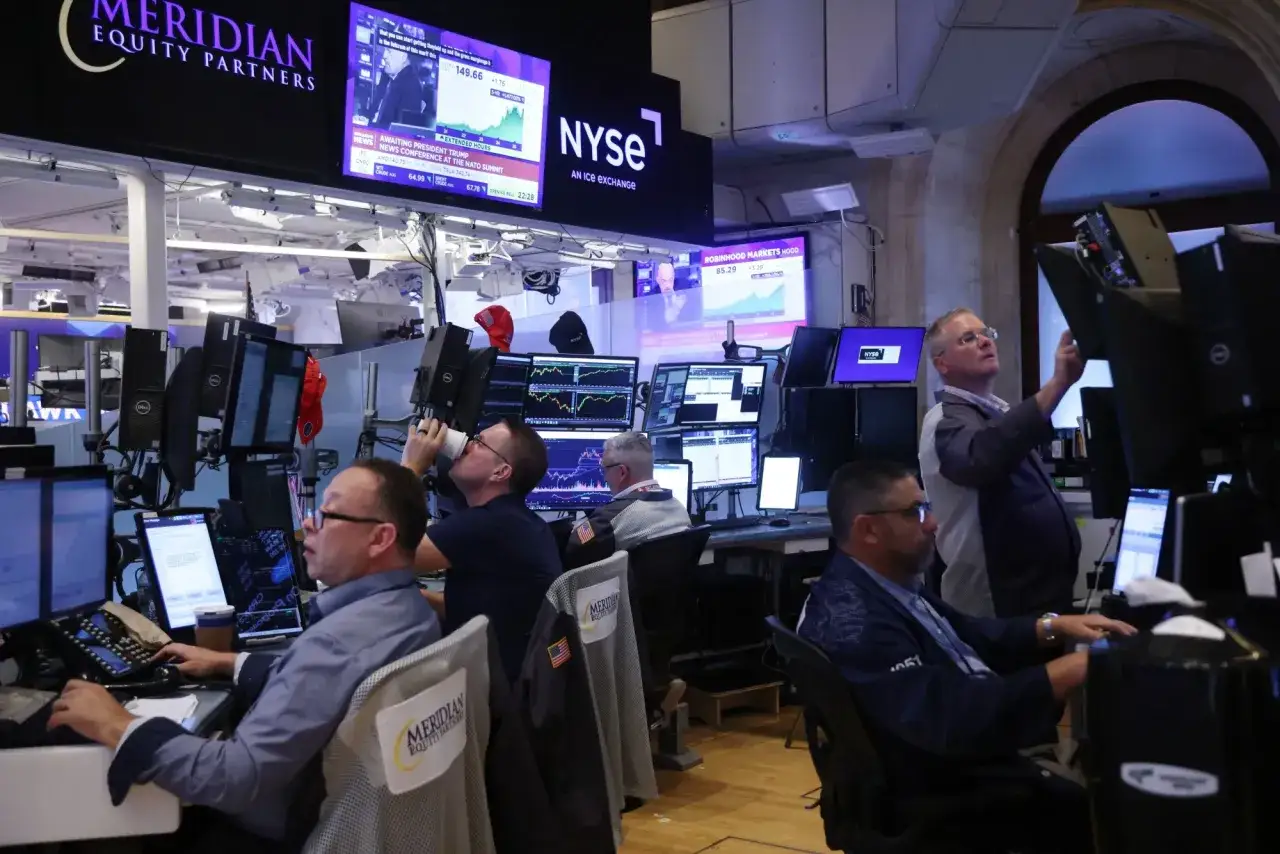 Trader Andrew Hall arbeitet im Börsenhandel, umgeben von Bildschirmen mit Aktienkursen und dem NYSE-Logo.