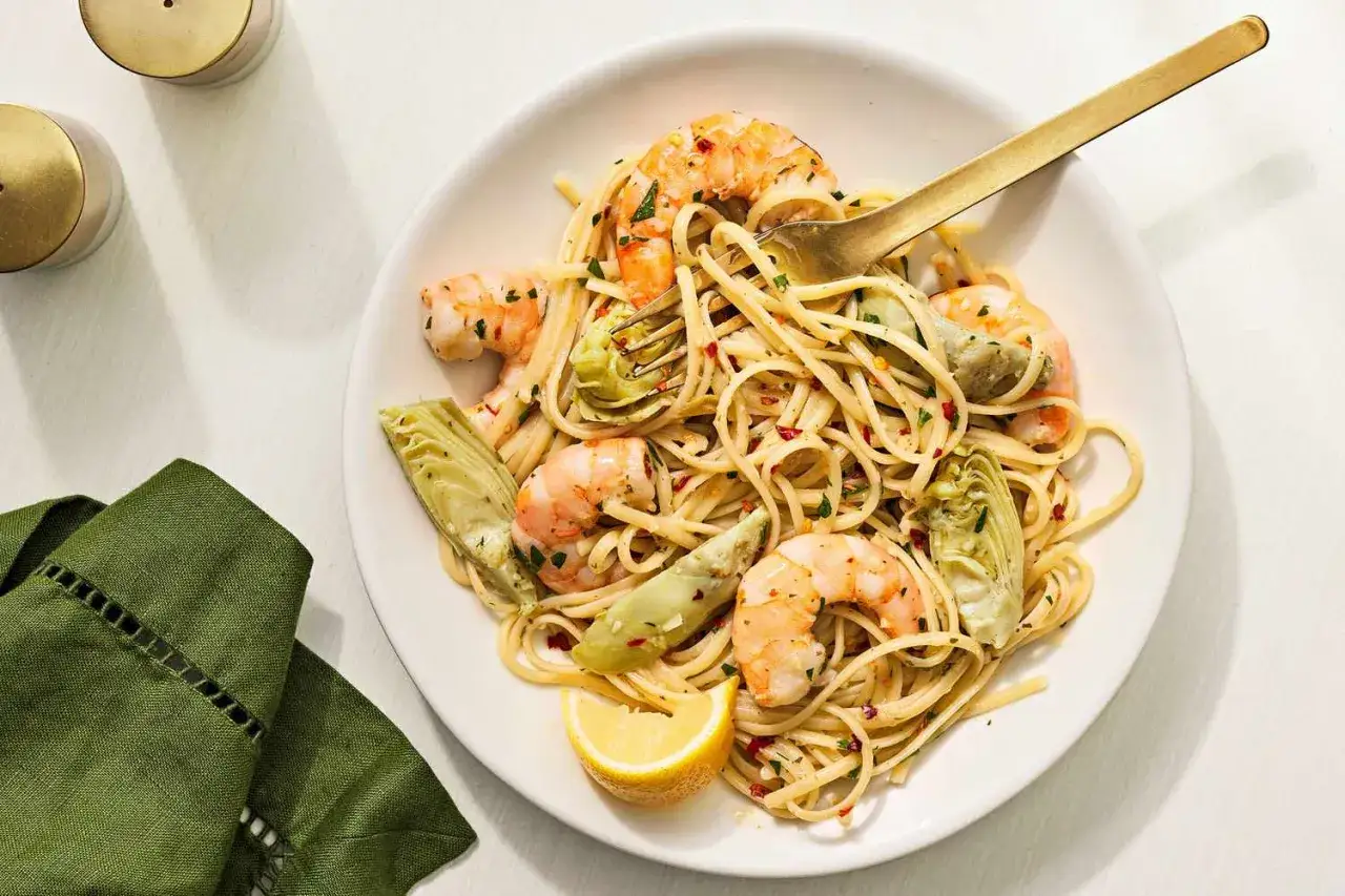 Szybkie danie na gorąco dla gości: linguine z krewetkami i karczochami, doprawione płatkami chili i cytryną.