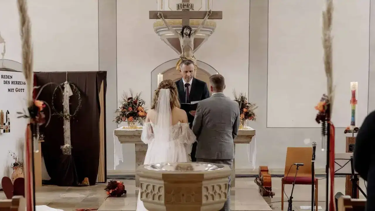 Ein Paar feiert seine gleichgeschlechtliche Ehe in der Kirche. Vor dem Altar, unter dem Kreuz, geben sie sich das Ja-Wort.