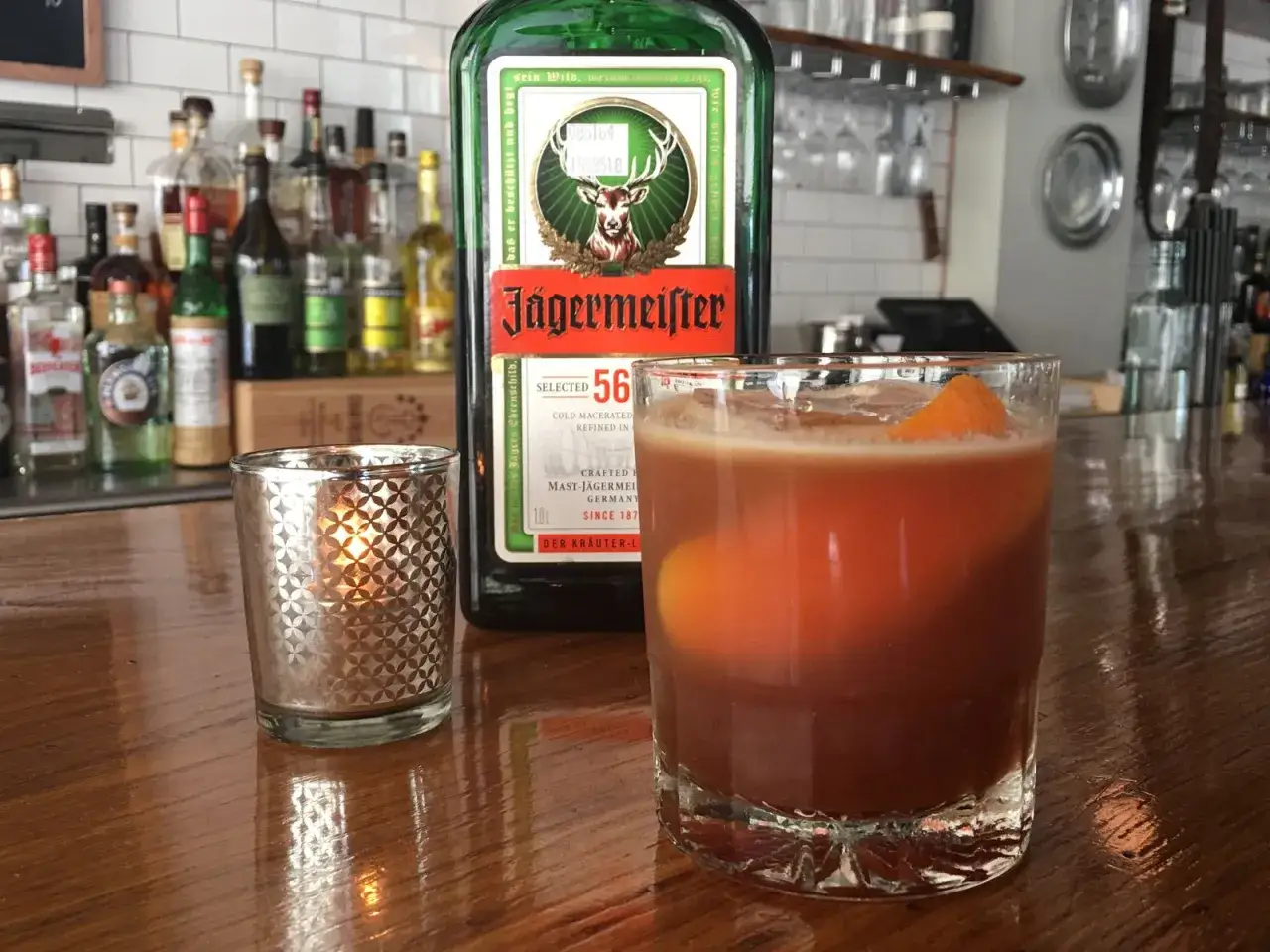 Jägermeister z pomarańczą i lodem, obok świecy. Idealny drink na wieczór.