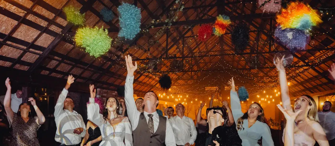 Wesele w pełni! Goście rzucają kolorowe peruki w powietrze, bawiąc się przy muzyce. Zastanawiasz się, ile kosztuje dj na wesele, by zapewnić taką atmosferę?