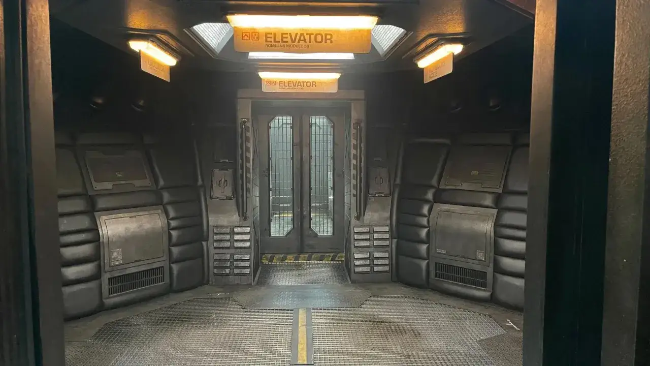 Der Aufzug auf dem Romulus-Modul 3B, bereit für den nächsten alien-romulus stream. Dunkle, gepolsterte Wände und ein Gitterboden.