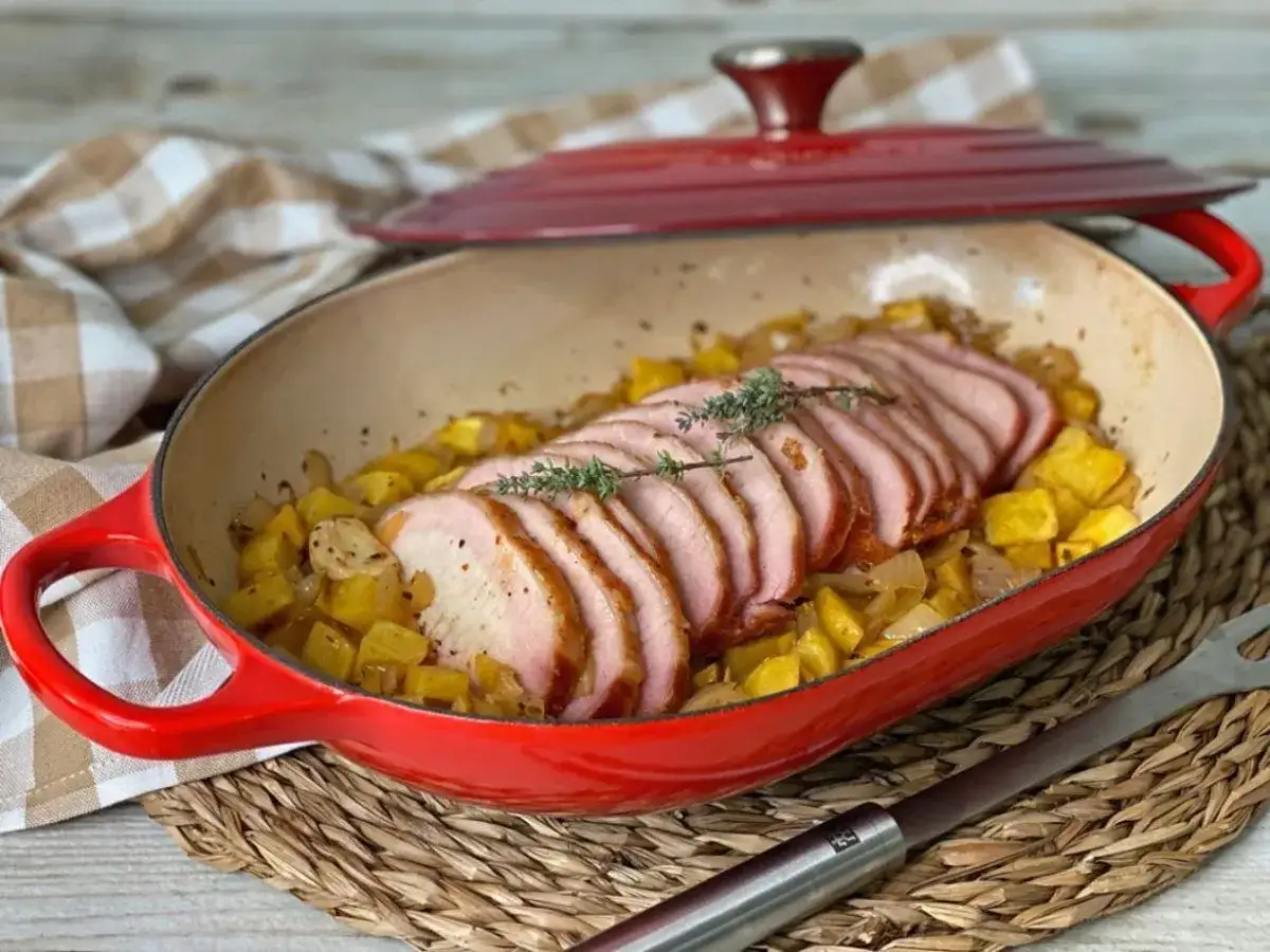 Lomo adobado jugoso y tierno, servido sobre patatas y cebolla doradas en una cazuela roja. &iexcl;Un plato delicioso!