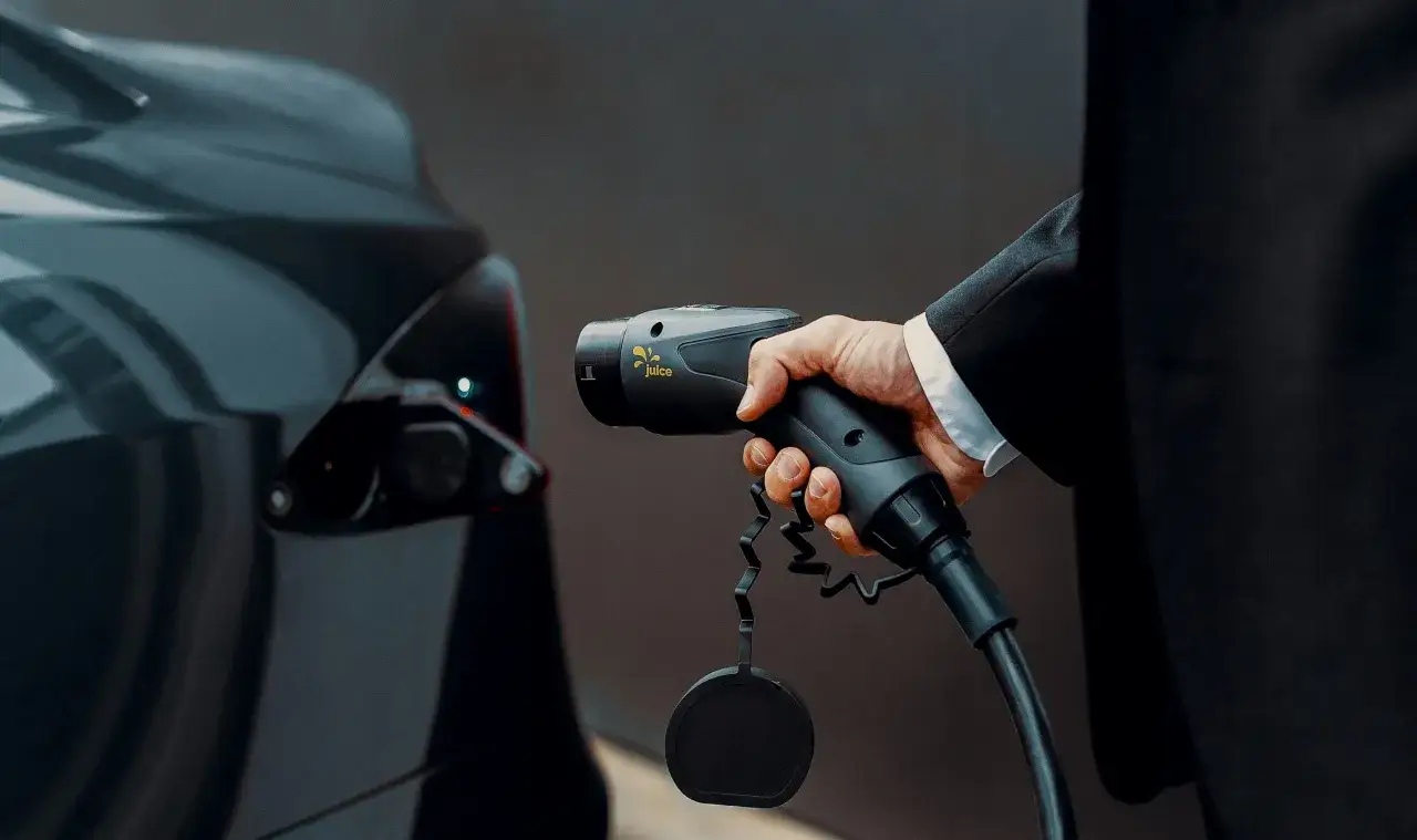 Mano desconectando el cargador del coche el&eacute;ctrico.