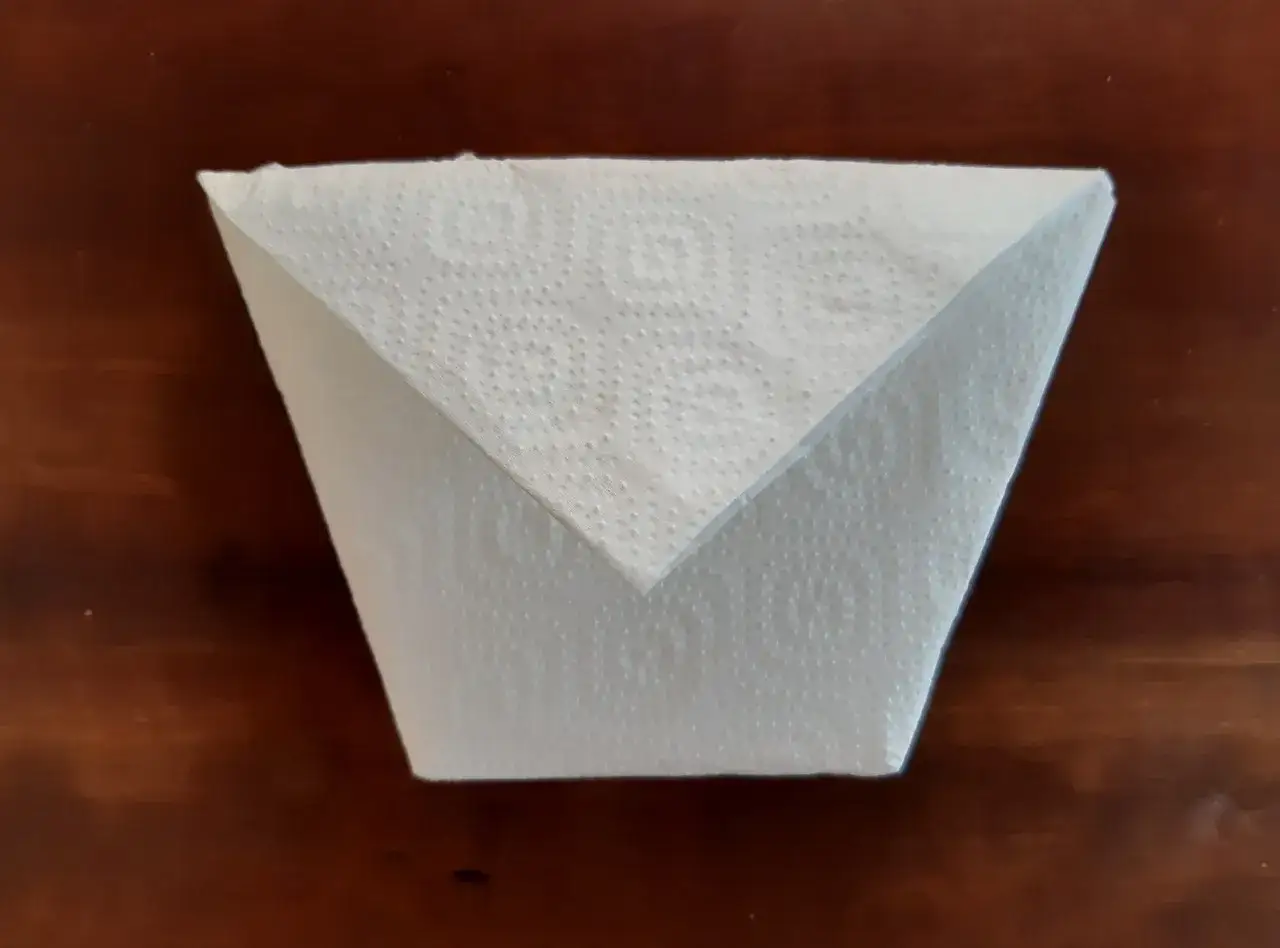 Ein gefalteter K&uuml;chenpapier-Kegel, der zeigt, wie man einen Kaffeefilter selber machen kann.