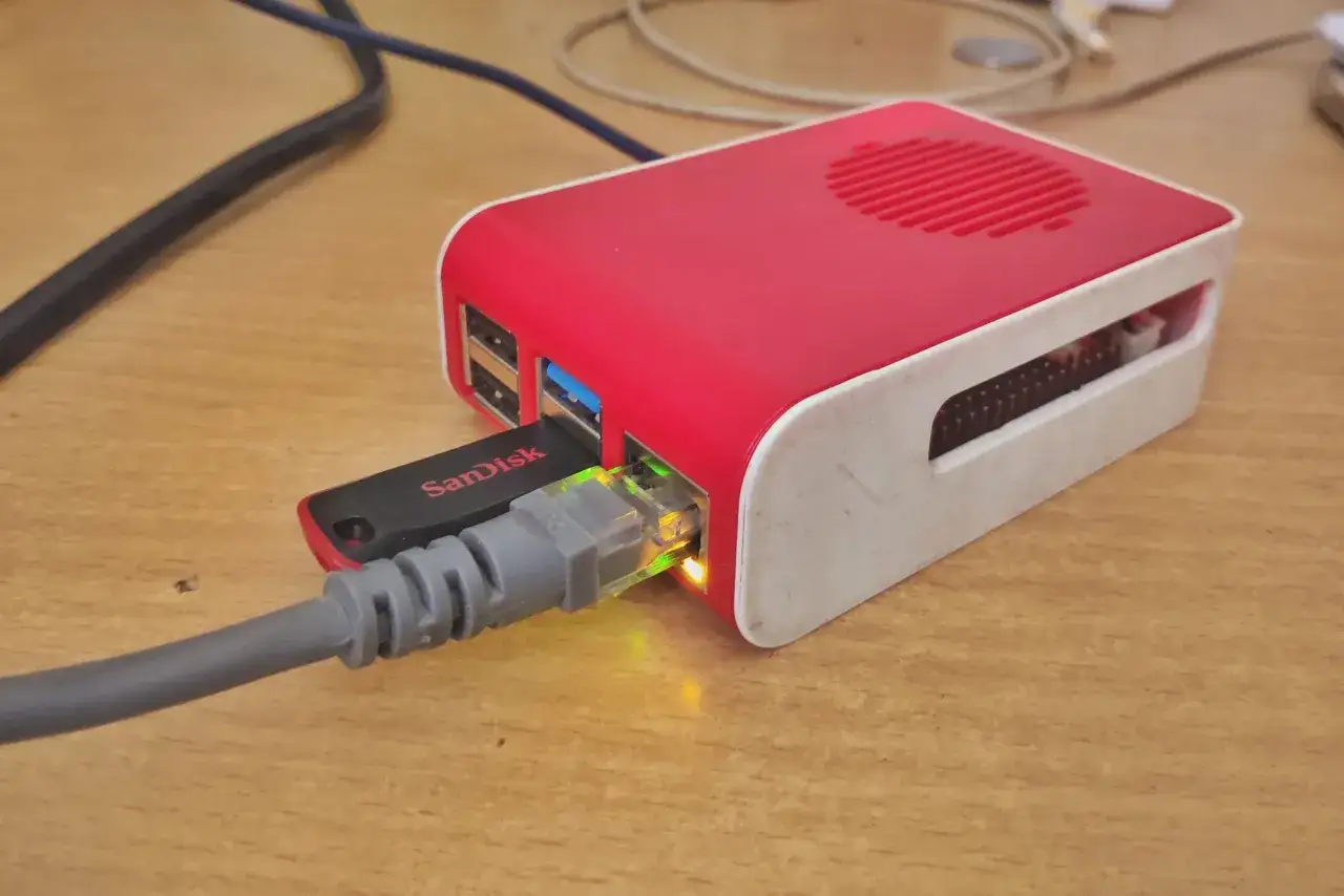 Ein rotes Raspberry Pi Geh&auml;use mit eingestecktem USB-Stick und Netzwerkkabel, bereit als NAS zu dienen.