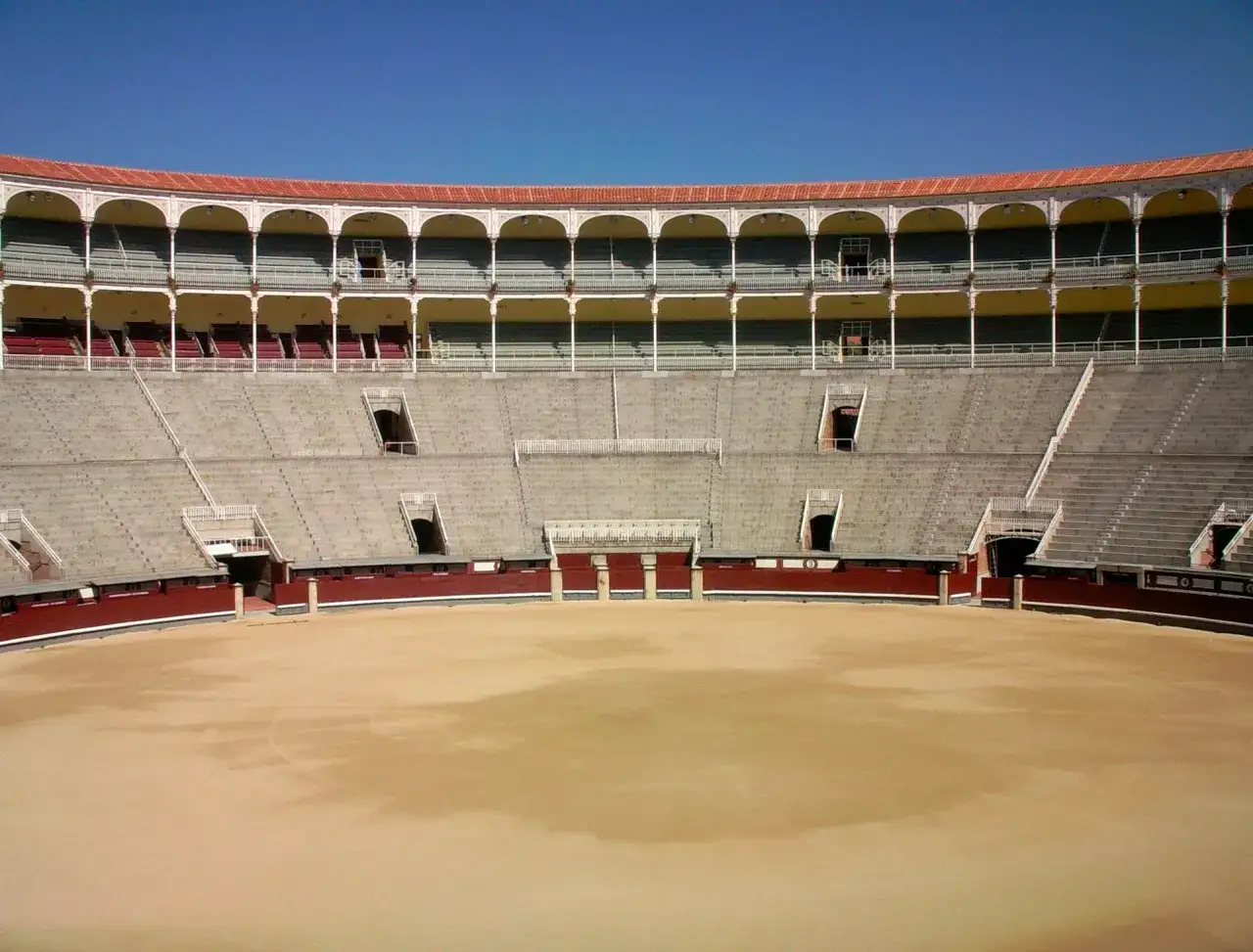 Arena vacía con gradas de piedra y balcones, lista para un evento con tendido alto las ventas.