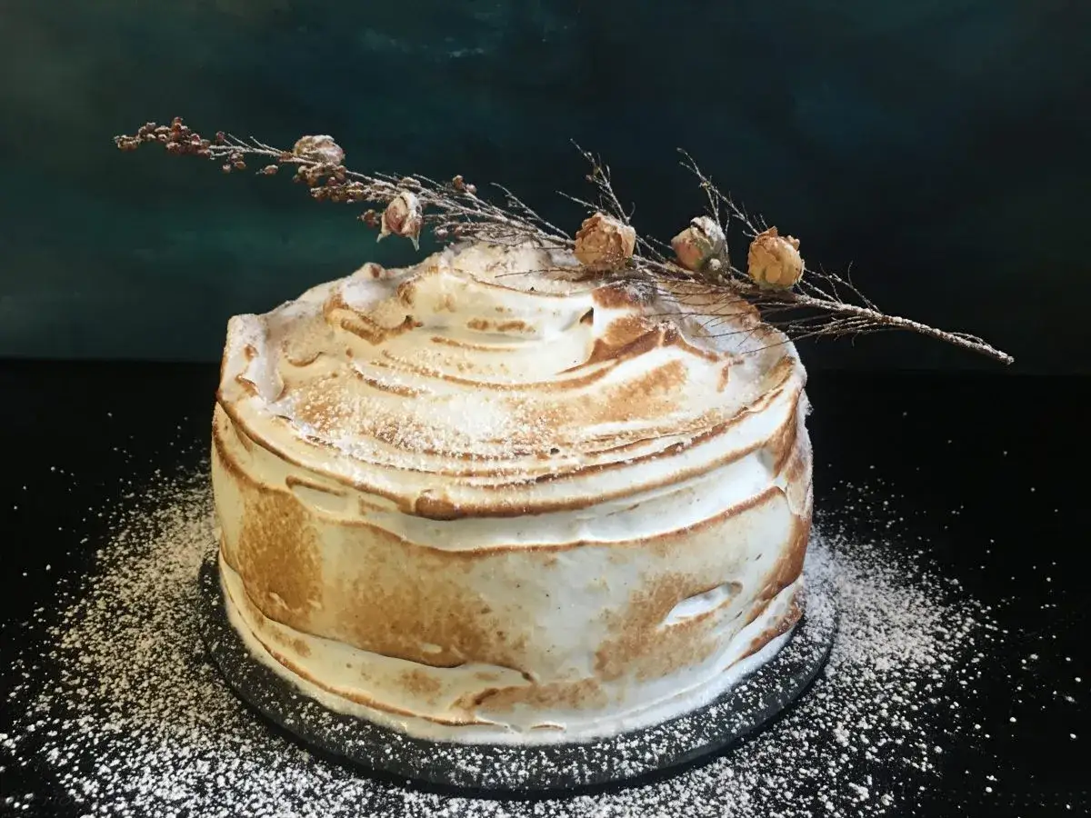 Gâteau rond recouvert d'une meringue dorée, décoré d'une branche sèche et de quelques petites fleurs. Une délicieuse crème diplomate mascarpone pour un dessert gourmand.