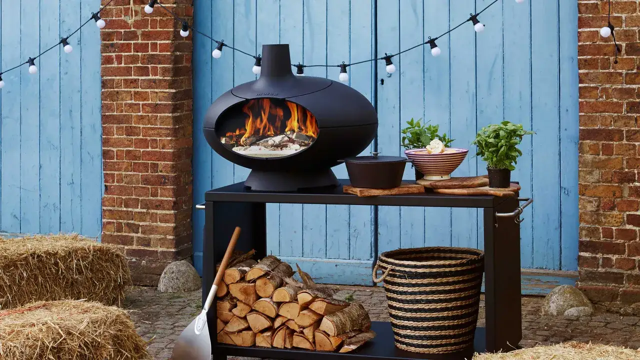 Un barbecue d'hiver avec un feu vif, du bois empilé, des herbes fraîches et des guirlandes lumineuses.
