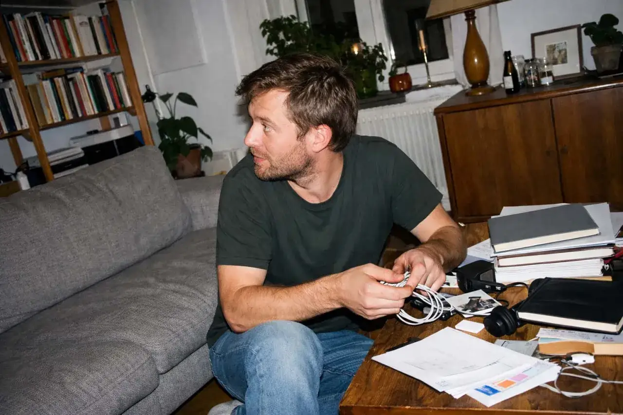 Man med sk&auml;gg sitter vid ett skrivbord med papper och b&ouml;cker. Han jobbar hemifr&aring;n med sitt eget uttag som enskild firma.