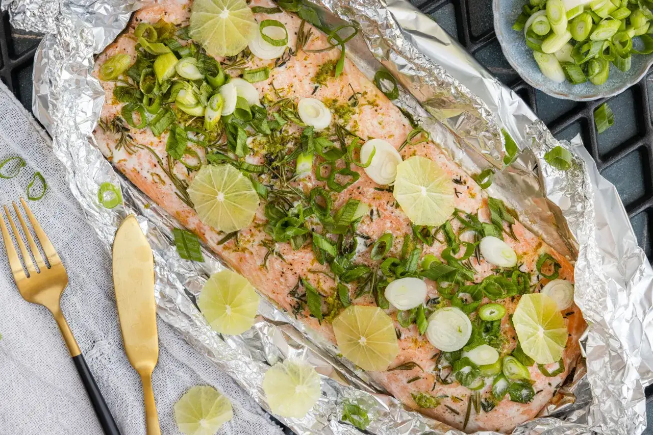 Lachsfilet grillen in Alufolie mit Limettenscheiben und Frühlingszwiebeln. Ein köstliches Gericht, bereit für den Grill.