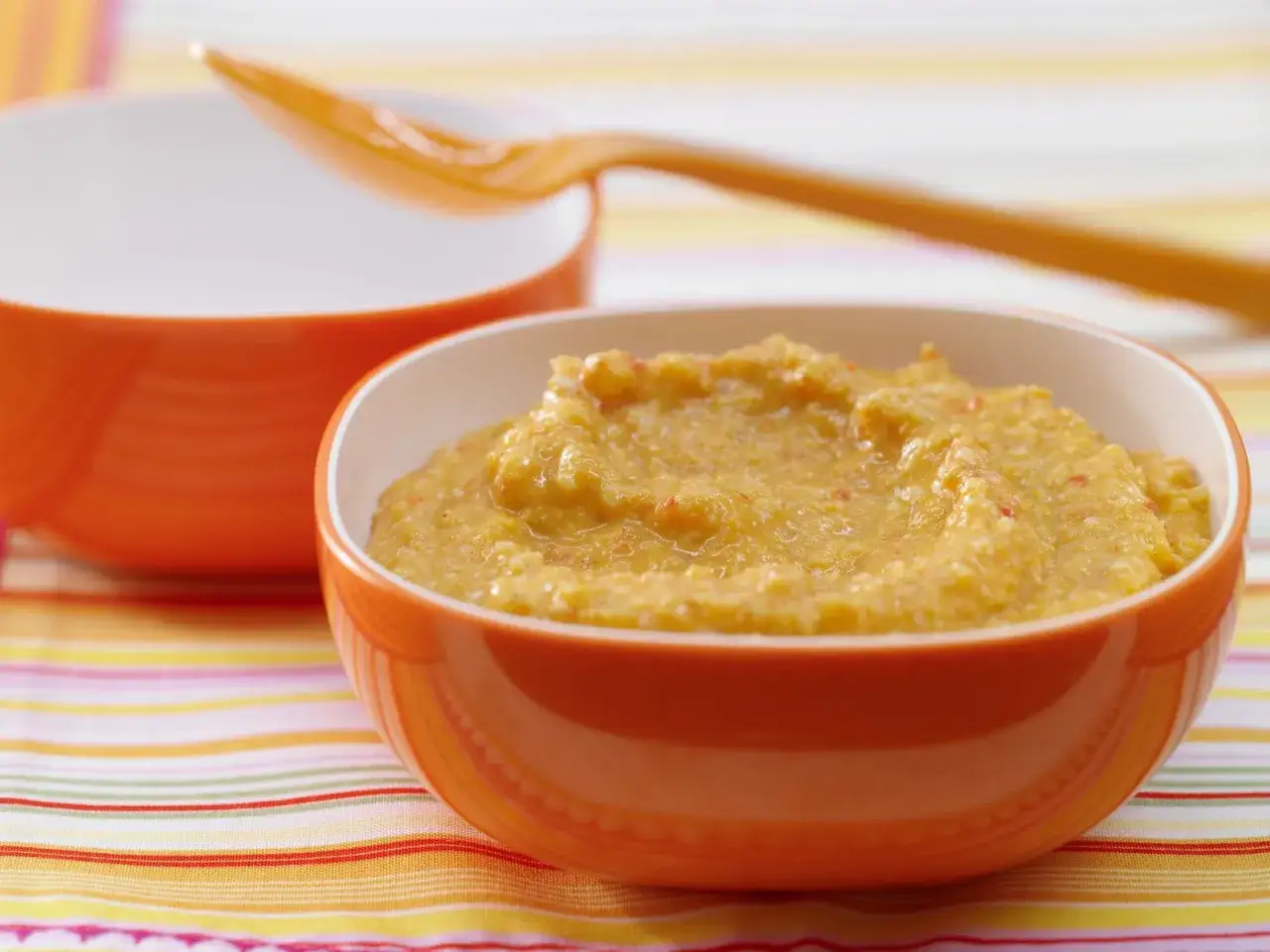 Brei mit Paprika für Babys: ab wann ist das eine gute Idee? Hier ein leckerer Brei in einem orangen Schälchen.