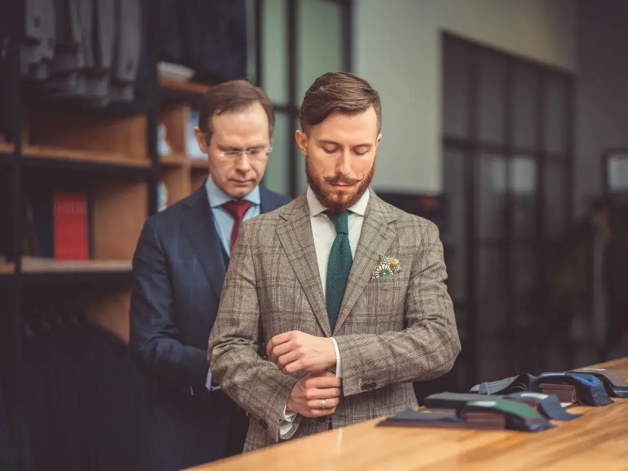 Elegancki garnitur dla świadka, dopasowany przez krawca. Mężczyzna w kratę i zielony krawat.