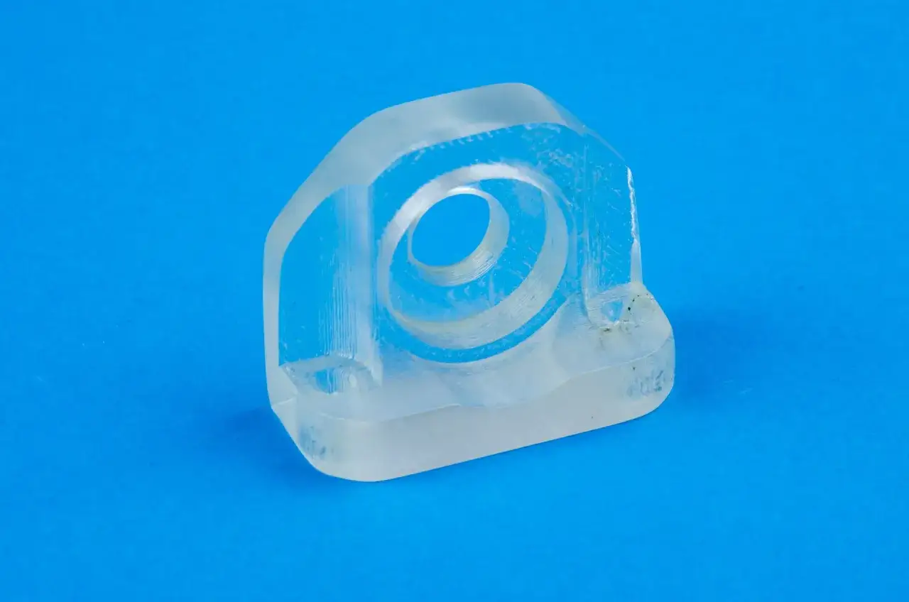 A clear, 3d printer acrylic part with a circular opening, showcasing intricate layers and a smooth finish on a vibrant blue background.