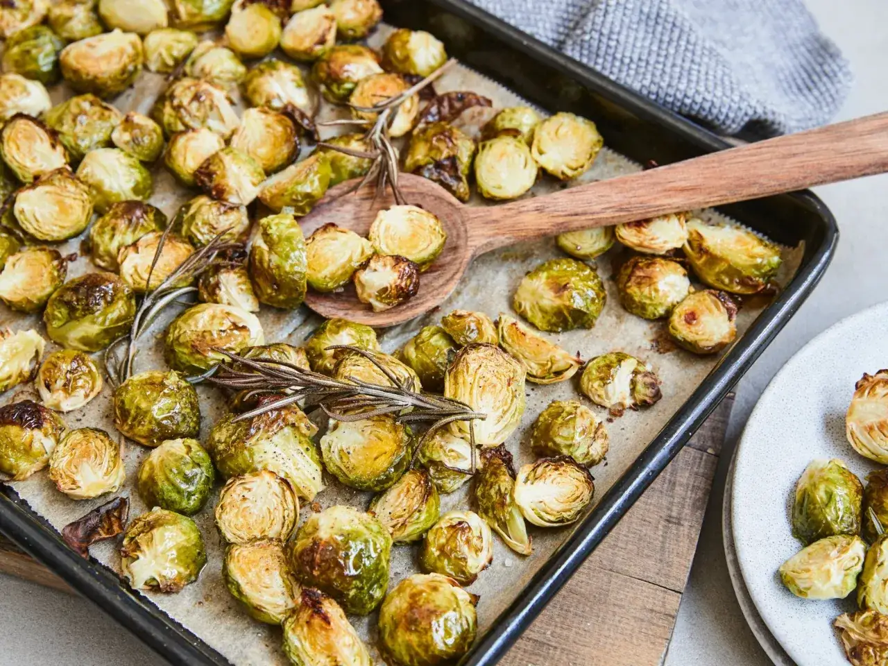 Ger&ouml;steter Rosenkohl mit Rosmarin, eine k&ouml;stliche Beilage zu Fleisch, liegt auf einem Backblech.