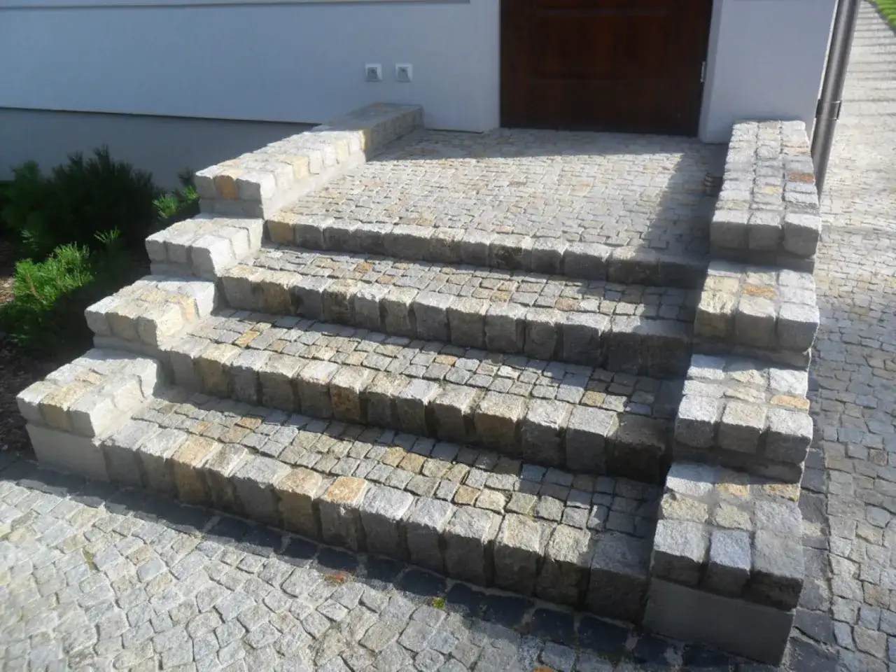 Solidne schody z kostki granitowej prowadzące do drzwi.