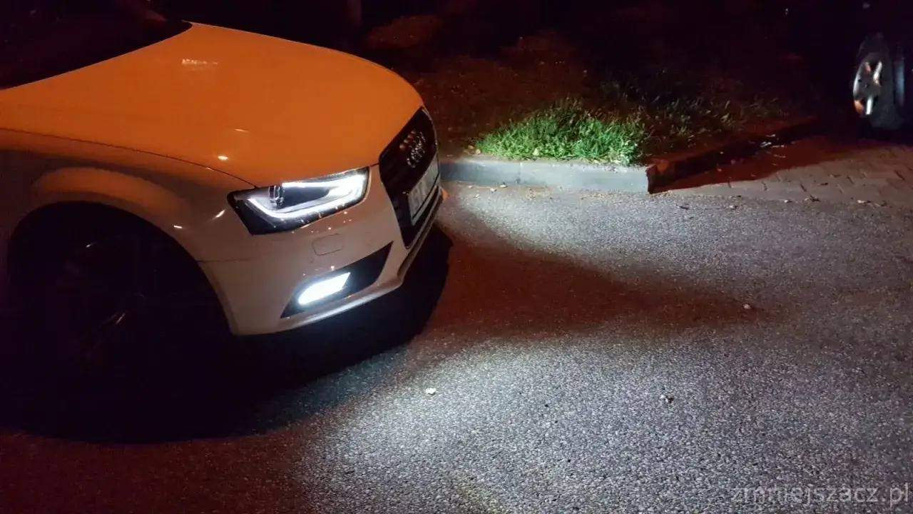 Białe Audi A4 B8 po lifcie z zapalonymi światłami przeciwmgielnymi. Wymiana żar&oacute;wki przeciwmgielnej zakończona sukcesem.