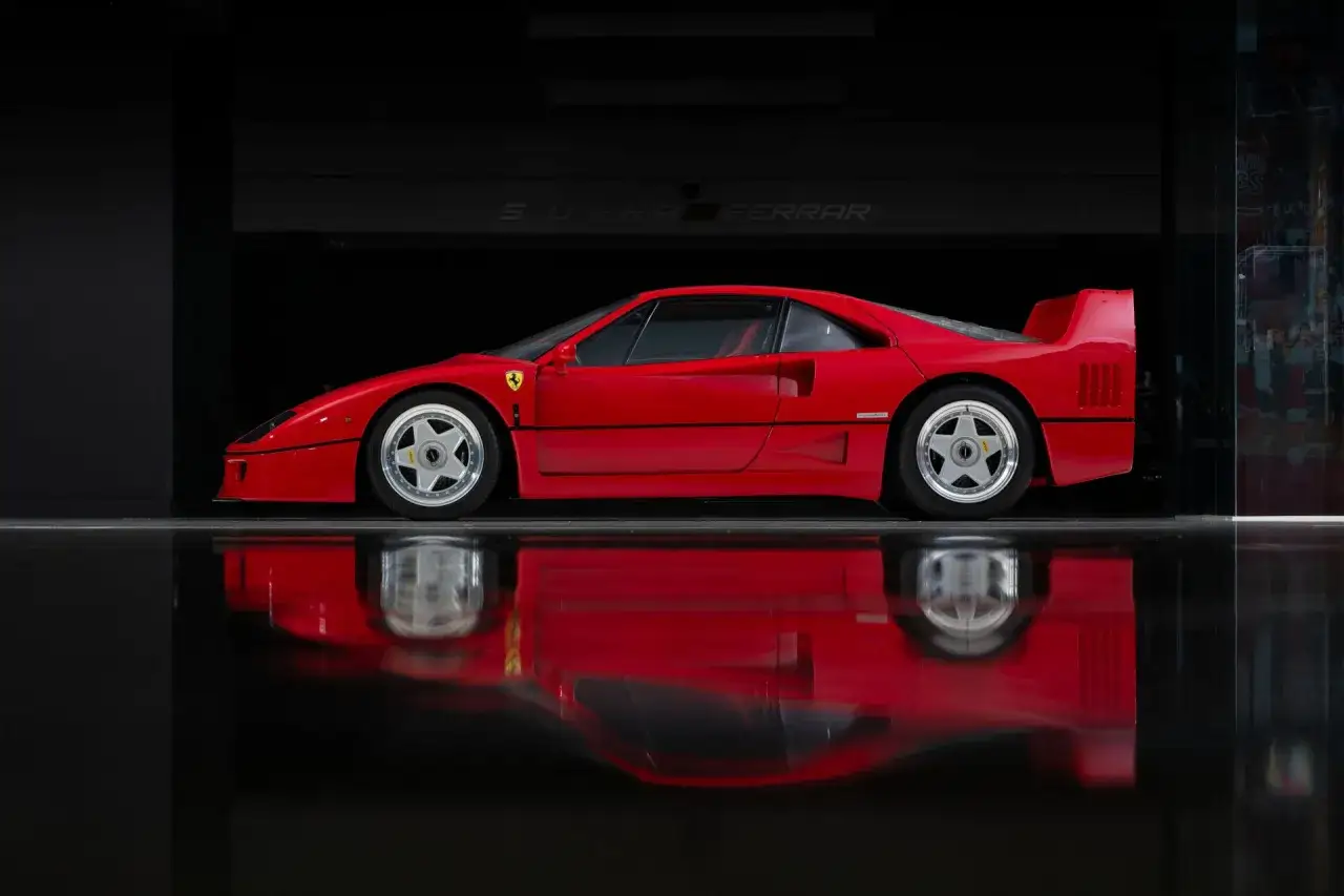 Roter Ferrari F40, ein ikonischer Sportwagen, spiegelt sich auf gl&auml;nzendem Boden.