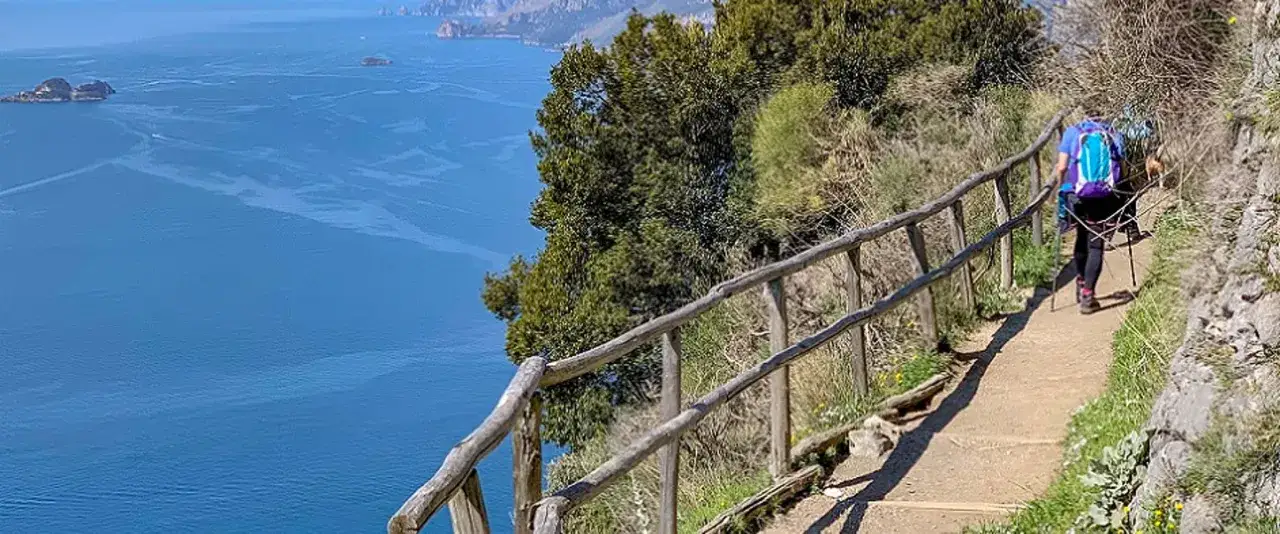 Escursionista sul sentiero degli dei ad Agerola, con vista sul mare blu e le montagne.