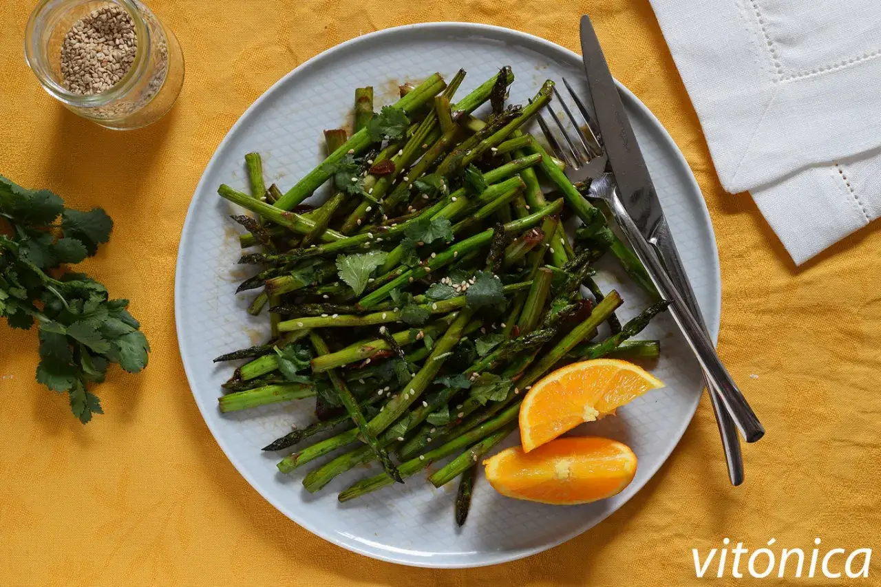 Esp&aacute;rragos verdes salteados con cilantro y s&eacute;samo, una idea deliciosa para tus recetas de esparragos verdes. Servidos con gajos de naranja.