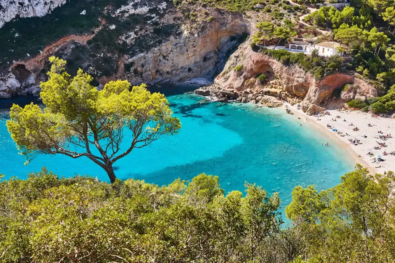 Cala con aguas turquesas y arena dorada, rodeada de acantilados y pinos. Un para&iacute;so entre las mejores playas Comunidad Valenciana.