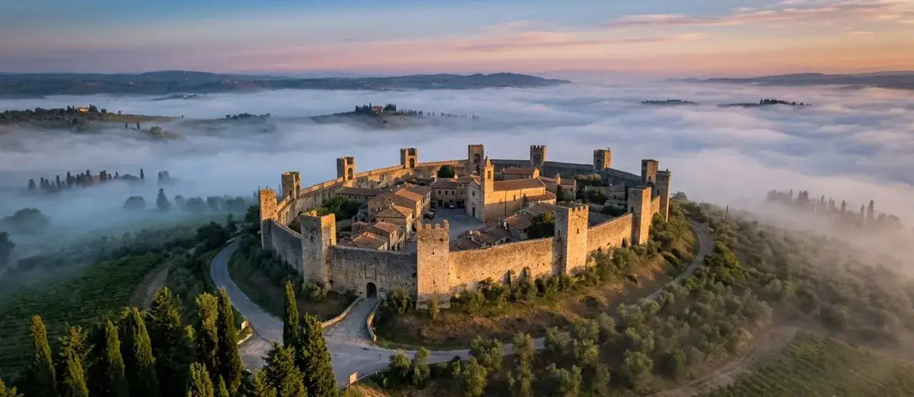 Borgo medievale fortificato immerso nella nebbia mattutina, un gioiello tra i paesi da visitare vicino a Bolgheri.