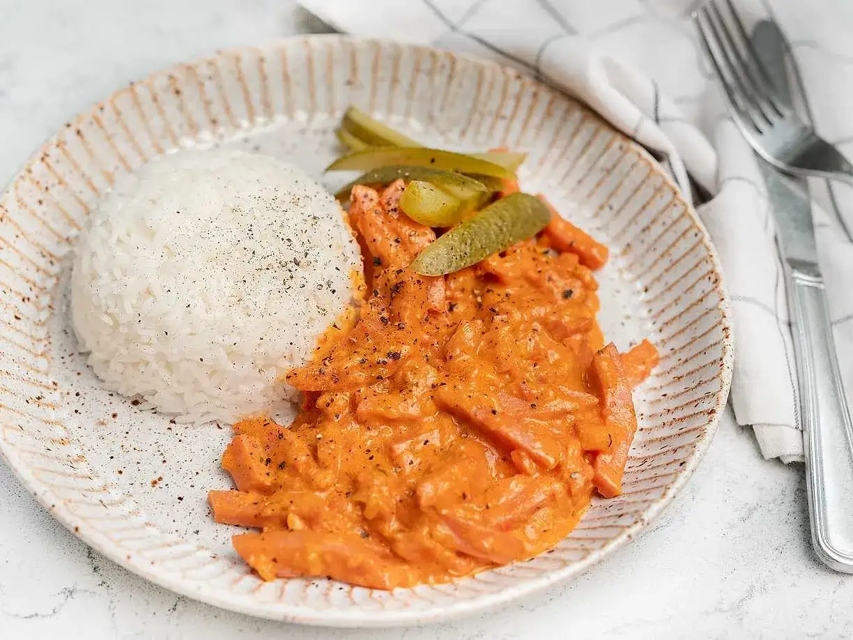 En portion kr&auml;mig korv stroganoff med ris och saltgurka. En klassisk svensk r&auml;tt som v&auml;rmer sj&auml;len.