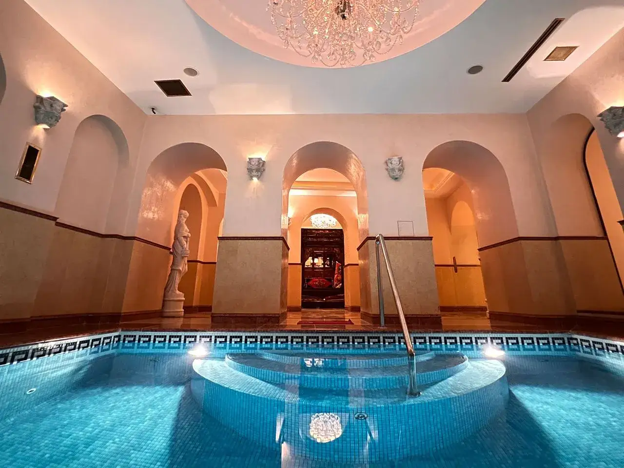 Ein luxuri&ouml;ser Poolbereich mit r&ouml;mischen B&ouml;gen und einer Statue, perfekt f&uuml;r einen entspannten Tschechien Urlaub mit Kindern.