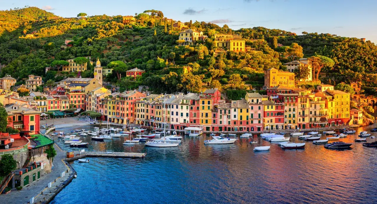 Kolorowe kamienice nad zatoką, gdzie leży Portofino, Liguria, Włochy. Łodzie kołyszą się na wodzie.