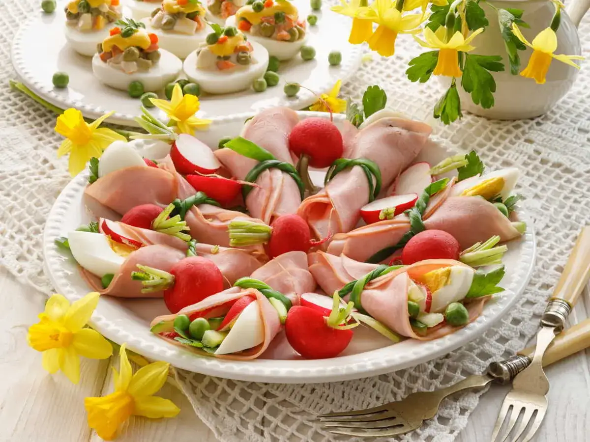 Une assiette d'entr&eacute;es traditionnelles de P&acirc;ques : rouleaux de jambon garnis de radis, &oelig;ufs durs et petits pois, d&eacute;cor&eacute;e de jonquilles.