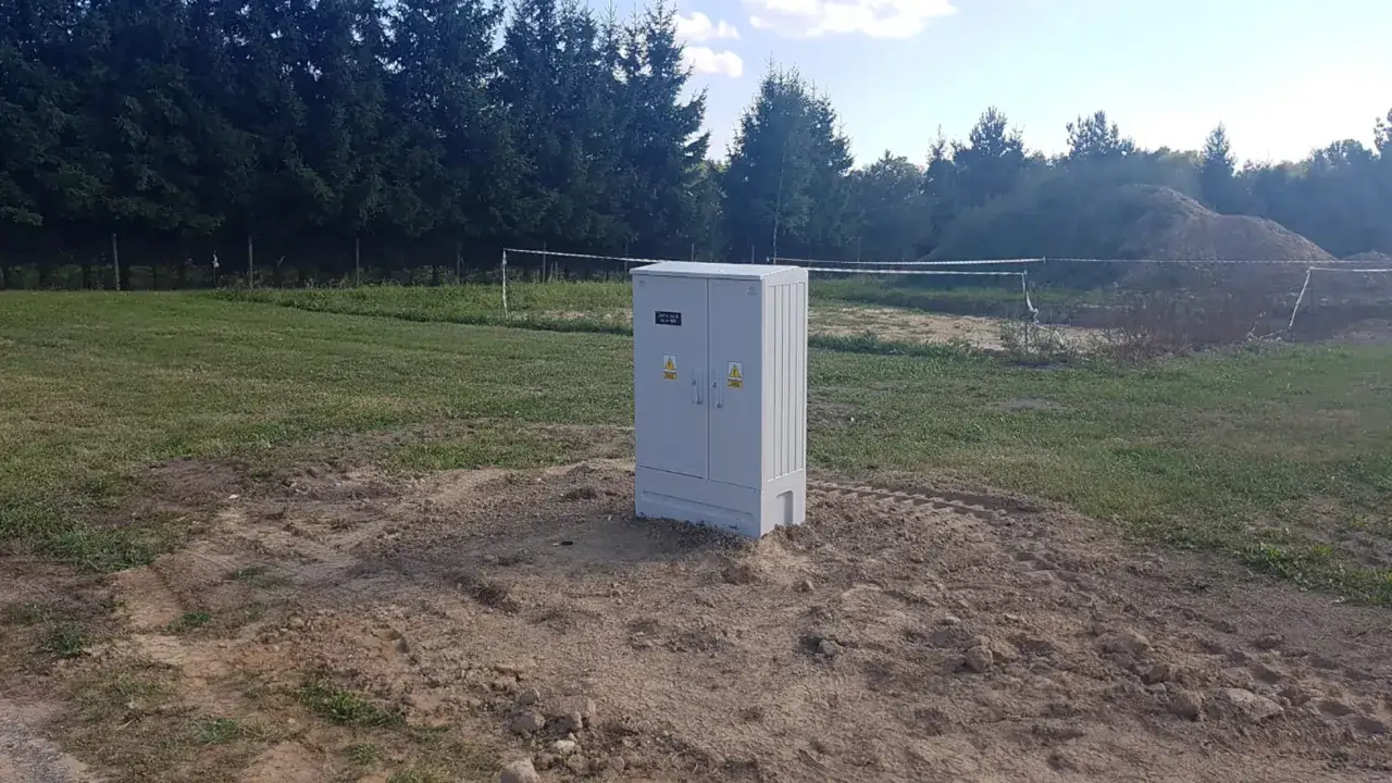 Szara skrzynka elektryczna na placu budowy. Zastanawiasz się, ile kosztuje uzbrojenie działki w prąd i wodę?