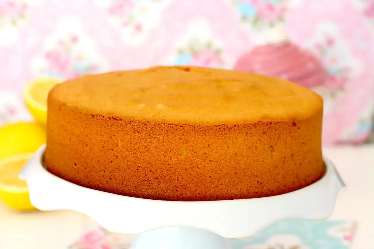 Bizcocho sin gluten, dorado y esponjoso, listo para decorar. Acompañado de limones frescos.