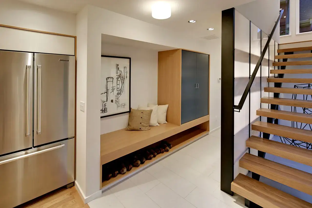 Ideas para decorar un pasillo interior: un banco de madera con almacenamiento para zapatos, un armario azul, un refrigerador y una escalera moderna.